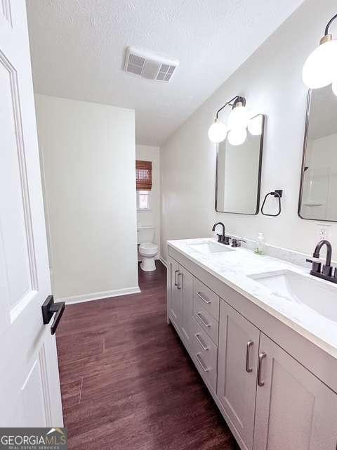 bathroom with vanity, wood-type flooring, a textured ceiling, and toilet