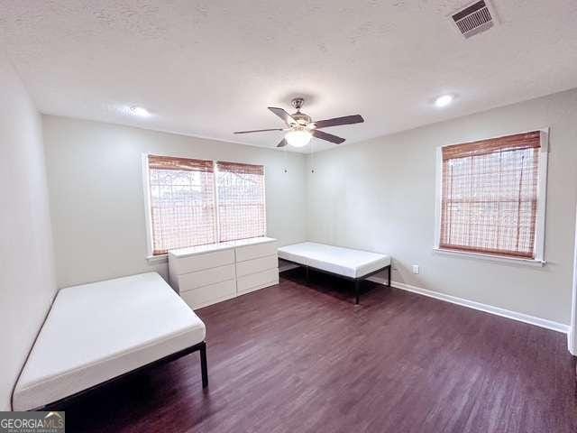 unfurnished bedroom with ceiling fan and dark wood-type flooring