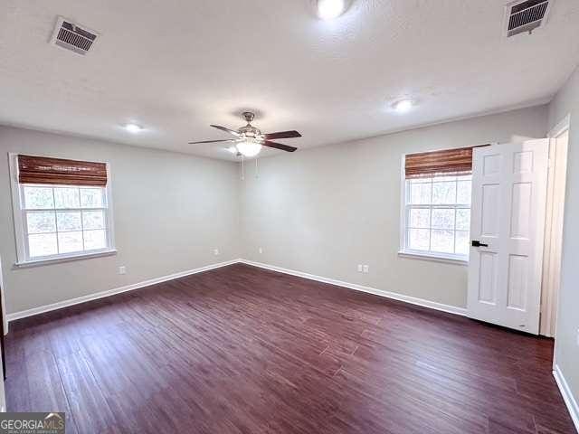 spare room featuring plenty of natural light, ceiling fan, and dark wood-type flooring