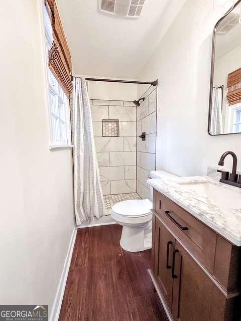 bathroom with walk in shower, hardwood / wood-style floors, vanity, and toilet