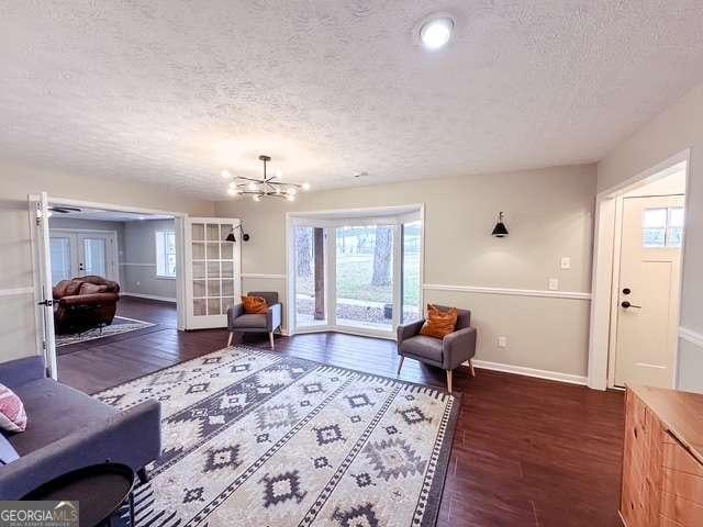 living room featuring a textured ceiling, french doors, dark hardwood / wood-style floors, and a notable chandelier