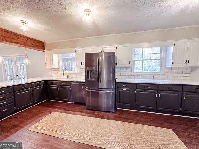 kitchen featuring white cabinets, a healthy amount of sunlight, dark hardwood / wood-style floors, and appliances with stainless steel finishes