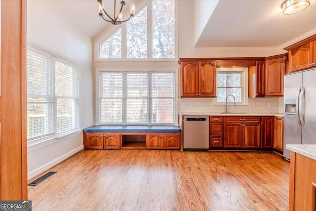 kitchen featuring stainless steel appliances, an inviting chandelier, a healthy amount of sunlight, and light hardwood / wood-style floors