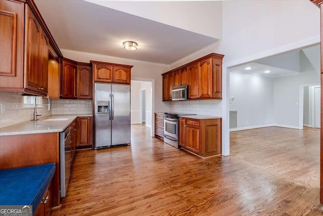 kitchen with decorative backsplash, stainless steel appliances, crown molding, sink, and hardwood / wood-style floors