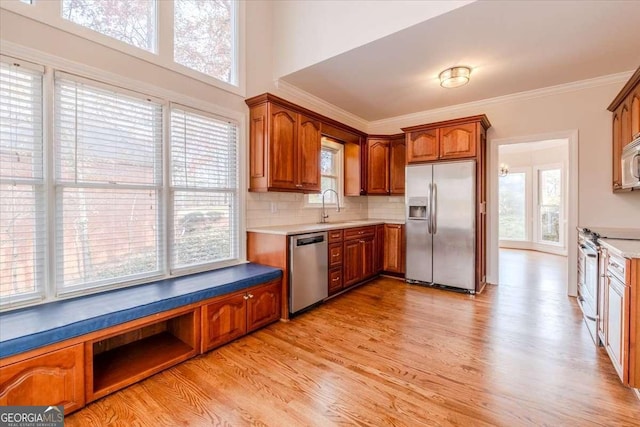 kitchen with light wood-type flooring, tasteful backsplash, stainless steel appliances, crown molding, and sink