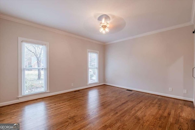 empty room with hardwood / wood-style flooring, a wealth of natural light, and ornamental molding