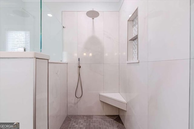 bathroom with a tile shower and tile walls