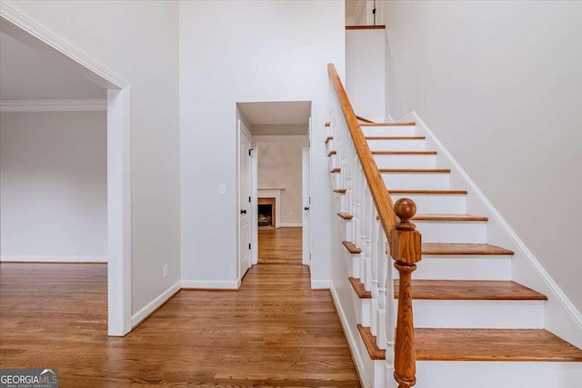 staircase with wood-type flooring and ornamental molding