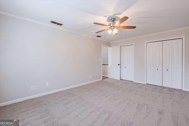 unfurnished bedroom featuring ceiling fan, crown molding, light carpet, and multiple closets