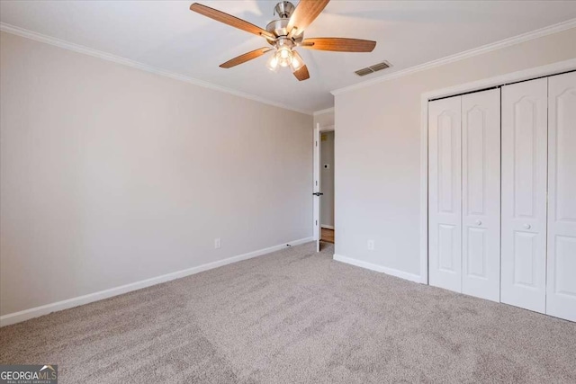 unfurnished bedroom featuring carpet flooring, ceiling fan, crown molding, and a closet