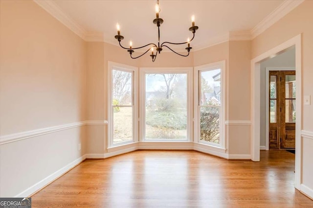 unfurnished dining area with a notable chandelier, light hardwood / wood-style floors, and crown molding