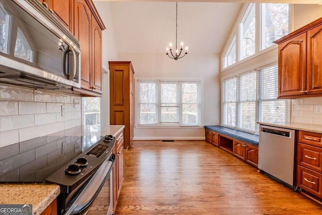 kitchen featuring a wealth of natural light, decorative backsplash, stainless steel appliances, and light hardwood / wood-style floors