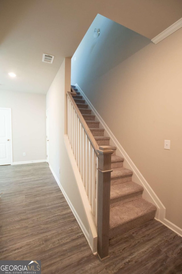 staircase with hardwood / wood-style floors and ornamental molding