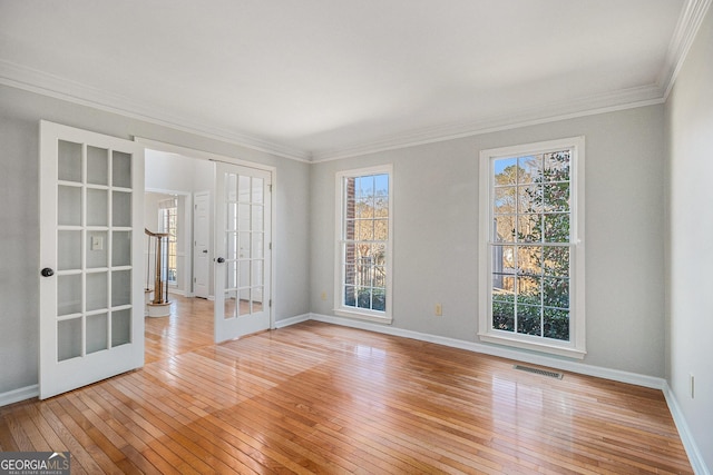 empty room with light wood-type flooring, a wealth of natural light, and french doors