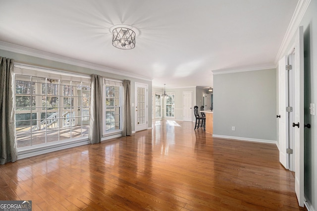 unfurnished living room with a chandelier, hardwood / wood-style floors, and crown molding