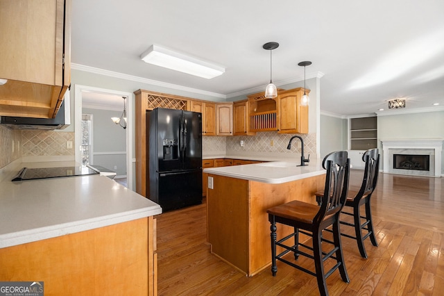 kitchen featuring kitchen peninsula, a breakfast bar, crown molding, sink, and black appliances