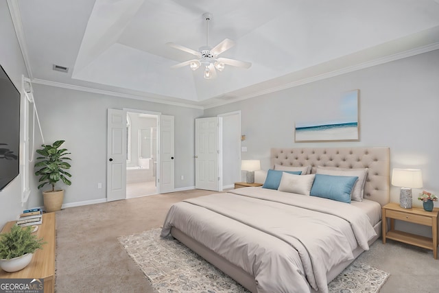 carpeted bedroom with a tray ceiling, ensuite bath, ceiling fan, and crown molding