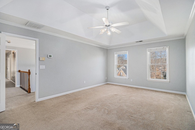 empty room featuring ceiling fan, light colored carpet, crown molding, and a tray ceiling