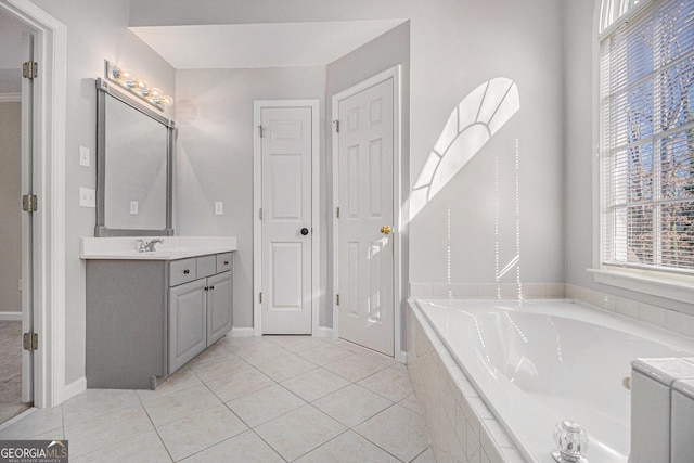 bathroom with tile patterned flooring, vanity, and a relaxing tiled tub