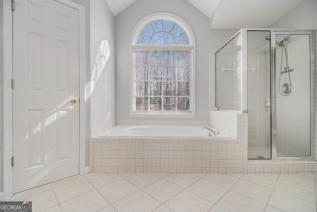 bathroom with tile patterned floors, plenty of natural light, independent shower and bath, and vaulted ceiling