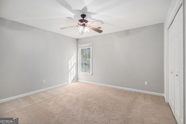 unfurnished bedroom featuring ceiling fan, a closet, and light carpet