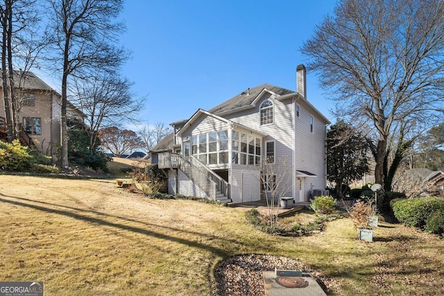 back of house featuring a lawn and a sunroom