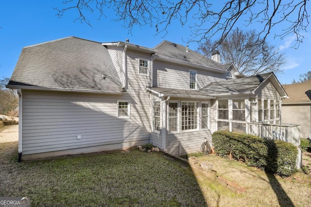 rear view of house featuring a lawn and a sunroom