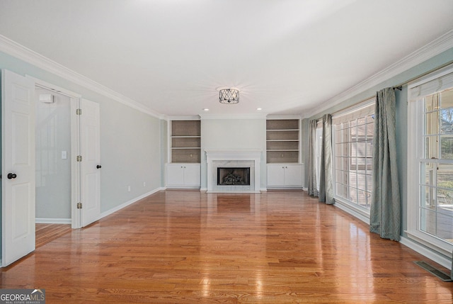 unfurnished living room featuring built in shelves, light wood-type flooring, and a fireplace