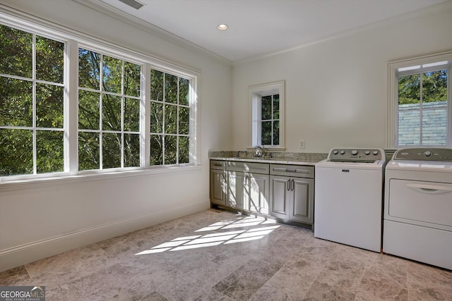 clothes washing area featuring cabinets, ornamental molding, sink, and washing machine and dryer