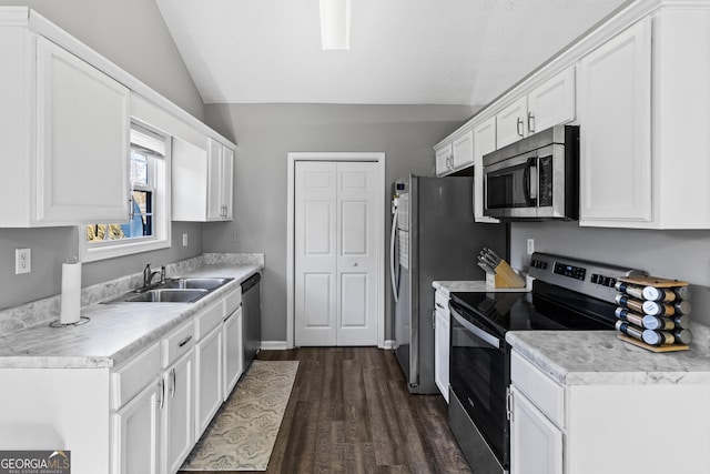 kitchen featuring dark hardwood / wood-style flooring, stainless steel appliances, vaulted ceiling, sink, and white cabinets