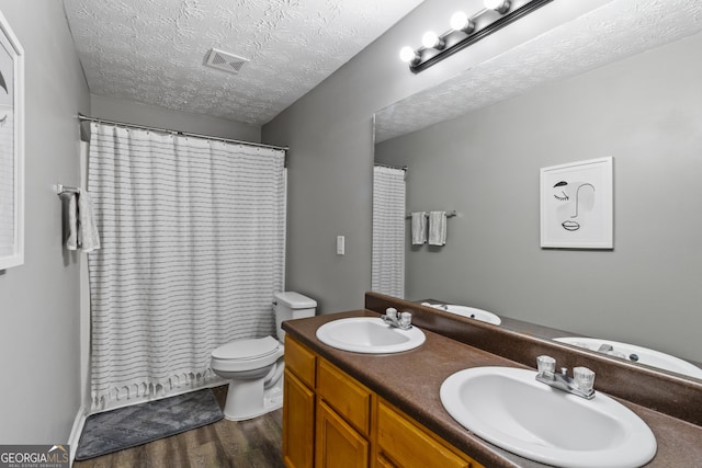 bathroom with hardwood / wood-style floors, a textured ceiling, toilet, vanity, and a shower with shower curtain