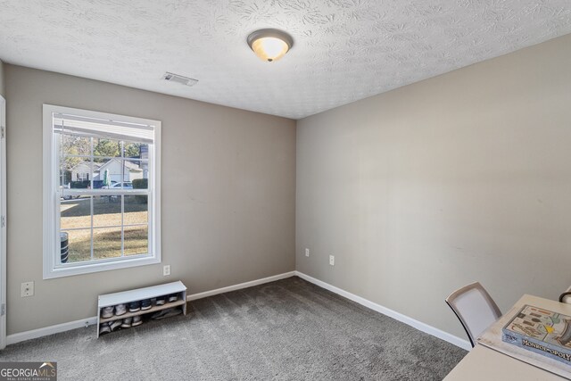 unfurnished office with dark carpet and a textured ceiling