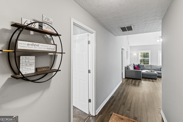 hall with a textured ceiling and dark hardwood / wood-style floors