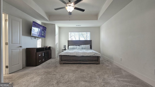 carpeted bedroom featuring ceiling fan and a tray ceiling