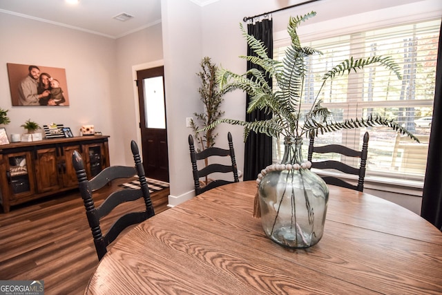 dining room with baseboards, visible vents, crown molding, and wood finished floors