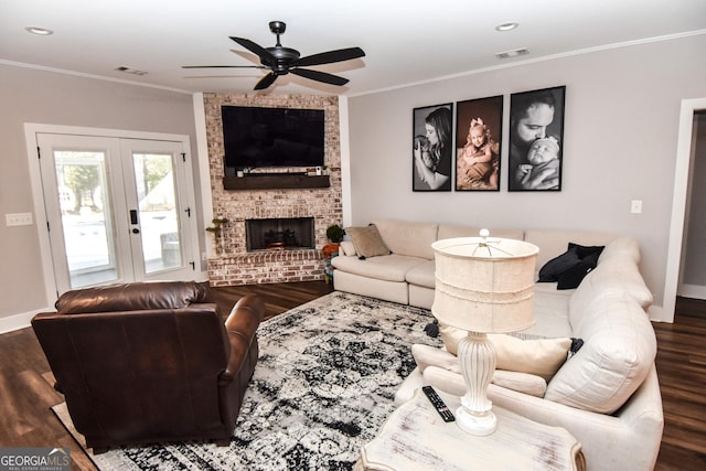 living area featuring crown molding, a fireplace, visible vents, wood finished floors, and baseboards