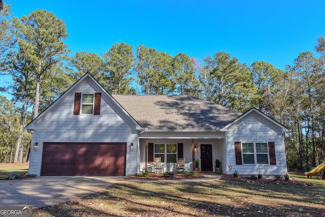 traditional home with a garage, driveway, a shingled roof, covered porch, and a front lawn