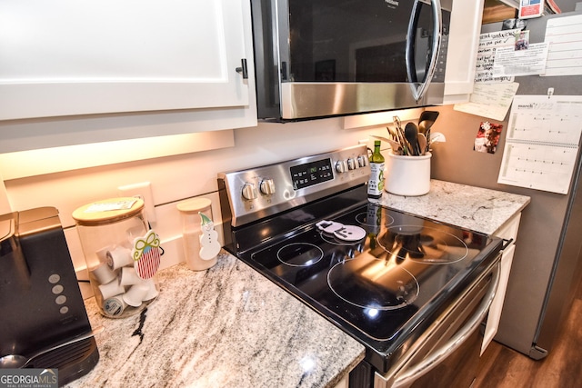 kitchen featuring stainless steel appliances, white cabinets, and light stone countertops