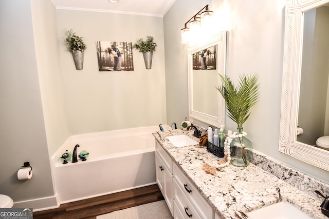 full bathroom with toilet, double vanity, a sink, and a bath