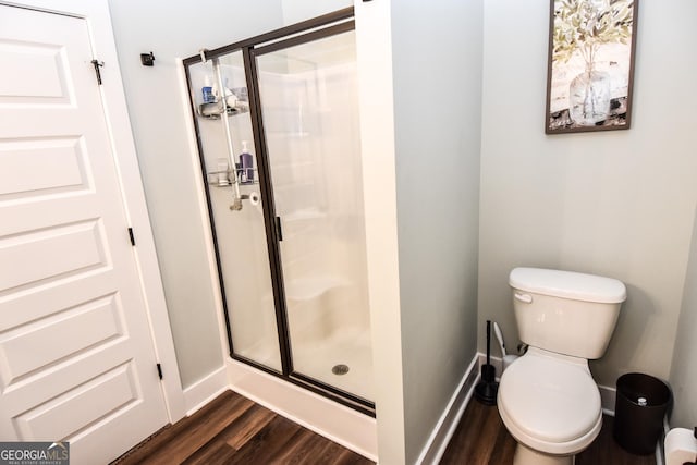 full bathroom with a stall shower, wood finished floors, toilet, and baseboards