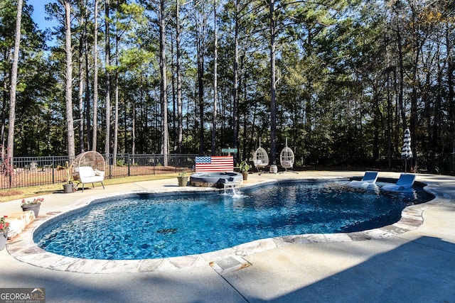 view of pool with a patio area, a pool with connected hot tub, and fence