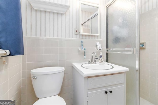 bathroom featuring an enclosed shower, vanity, toilet, and tile walls