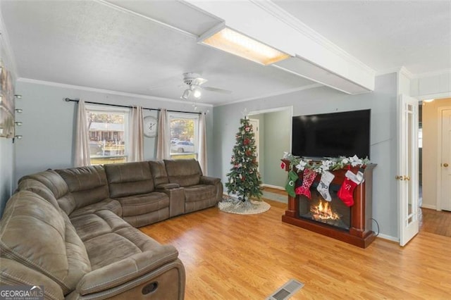 living room with light hardwood / wood-style flooring, ceiling fan, and ornamental molding