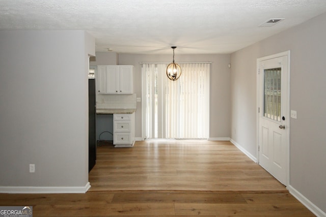 interior space with light hardwood / wood-style flooring, a chandelier, and a textured ceiling