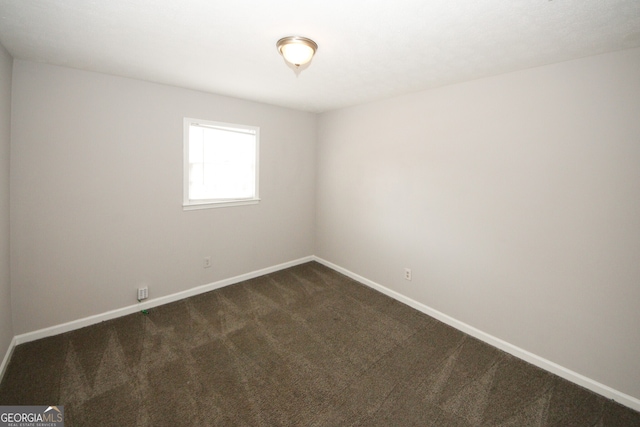 unfurnished room with dark colored carpet