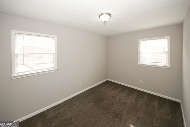 spare room with dark colored carpet and a healthy amount of sunlight