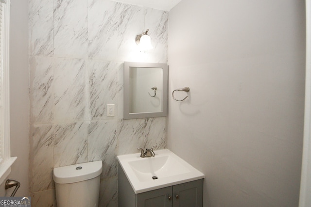 bathroom featuring vanity, toilet, and tile walls