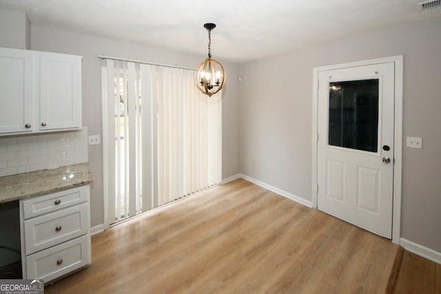 unfurnished dining area with light hardwood / wood-style floors and an inviting chandelier