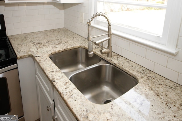 room details featuring electric range, decorative backsplash, light stone countertops, and sink