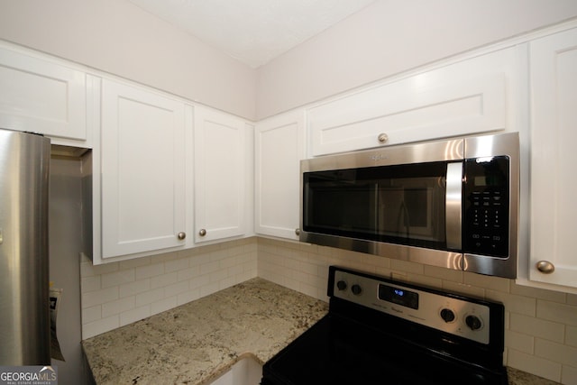 kitchen featuring white cabinets, backsplash, light stone counters, and stainless steel appliances